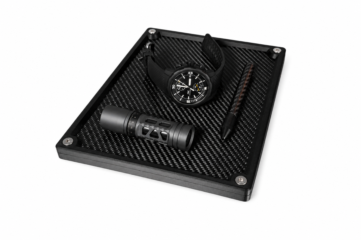 Large carbon fibre organiser tray storing many different everyday carry essentials on a desk.