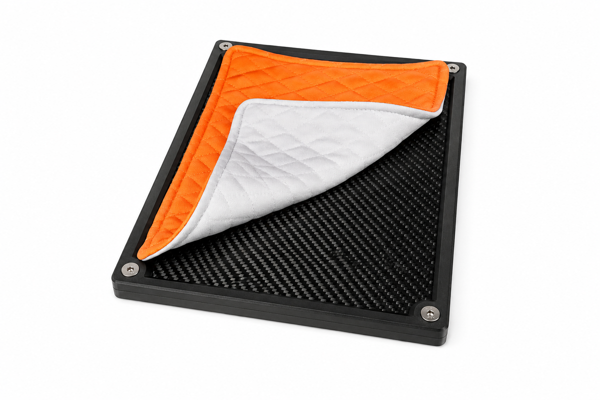 Folded papaya quilted valuables cloth highlighting the padded construction and stitching on a carbon fiber tray